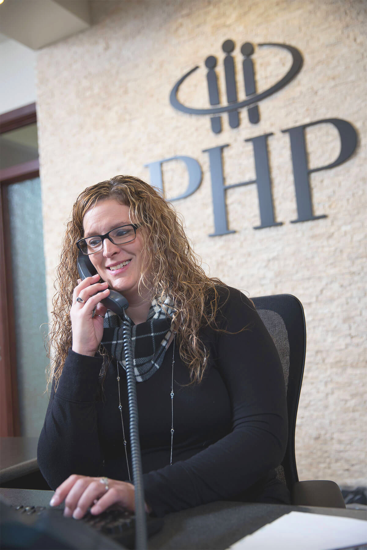 A receptionist at Physicians Health Plan is on the phone helping a customer.
