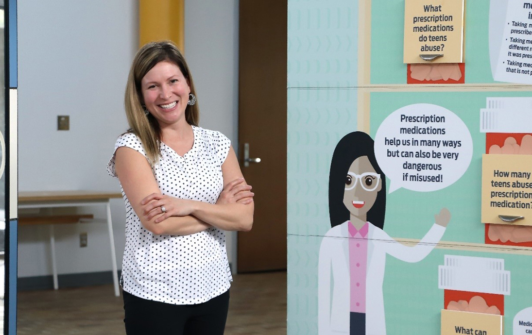 MBA Executive Director Nicole Fairchild stands next to a McMillen Health Informational Board